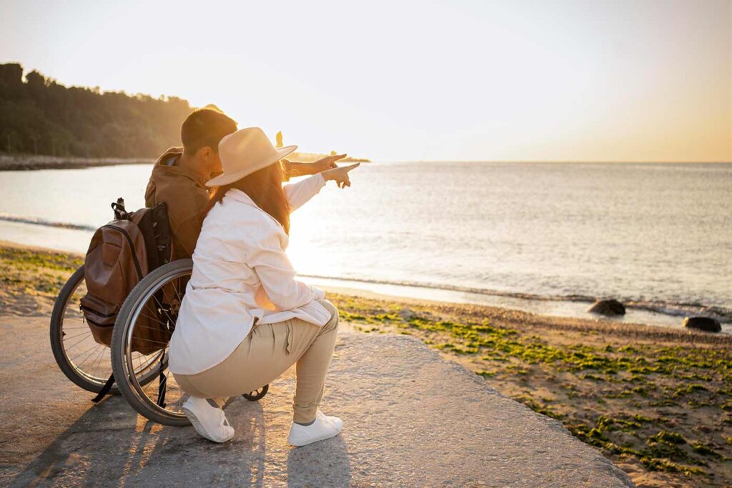 Mężczyzna na wózku inwalidzkim z kobietą nad morzem