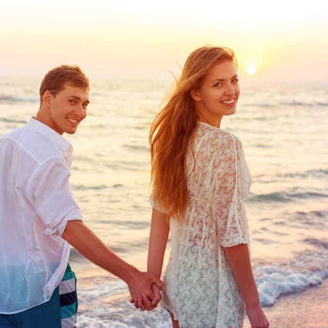 Para uśmiechająca się i spacerujaca po plaży